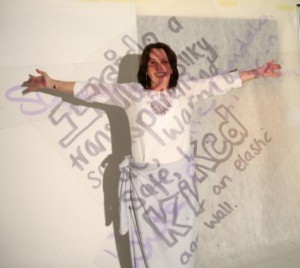 woman in white against white screen with poetry projected over her body