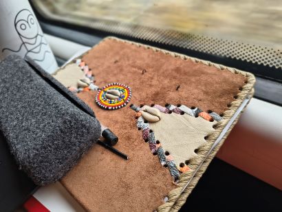 Kenyan suede and leather notebook with beading, glasses case and drink bottle with owl and water design. Taken on a train as the world outside blurs past.